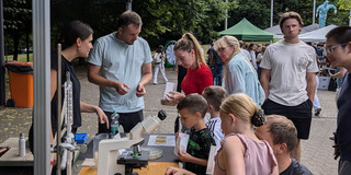 Besucher am Stand mit Destille, Mikroskop und Fangplatten