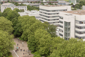 BCI-Gebäude BCI: Rechts im Bild befinden sich zwei hohe graue Gebäude mit vielen Fenstern der Fakultät Bio- und Chemieingenieurwesen. Davor und weiter links im Bild Bäume.